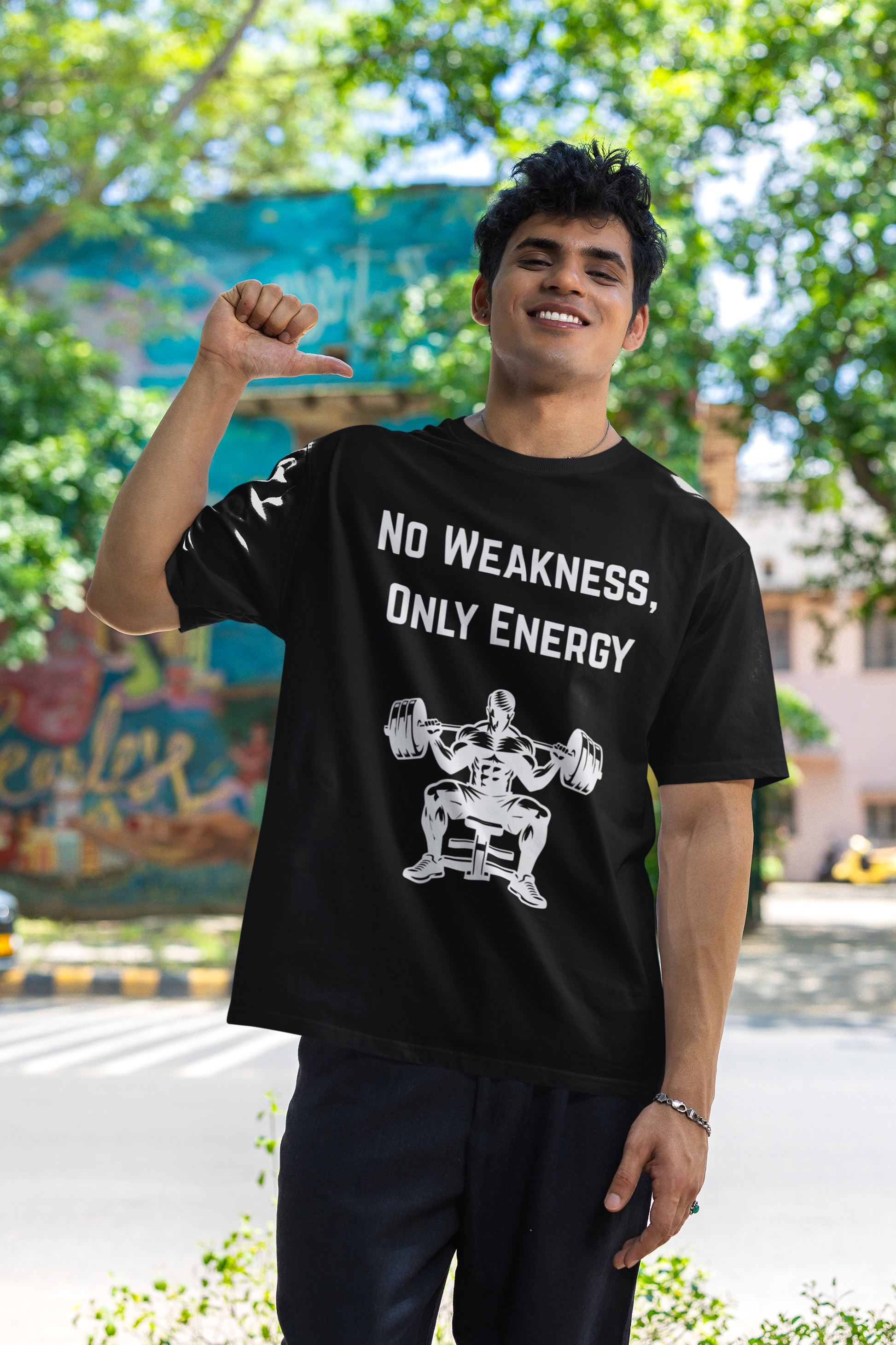 Man pointing at black t-shirt with No Weakness Only Energy text and bodybuilder graphic.