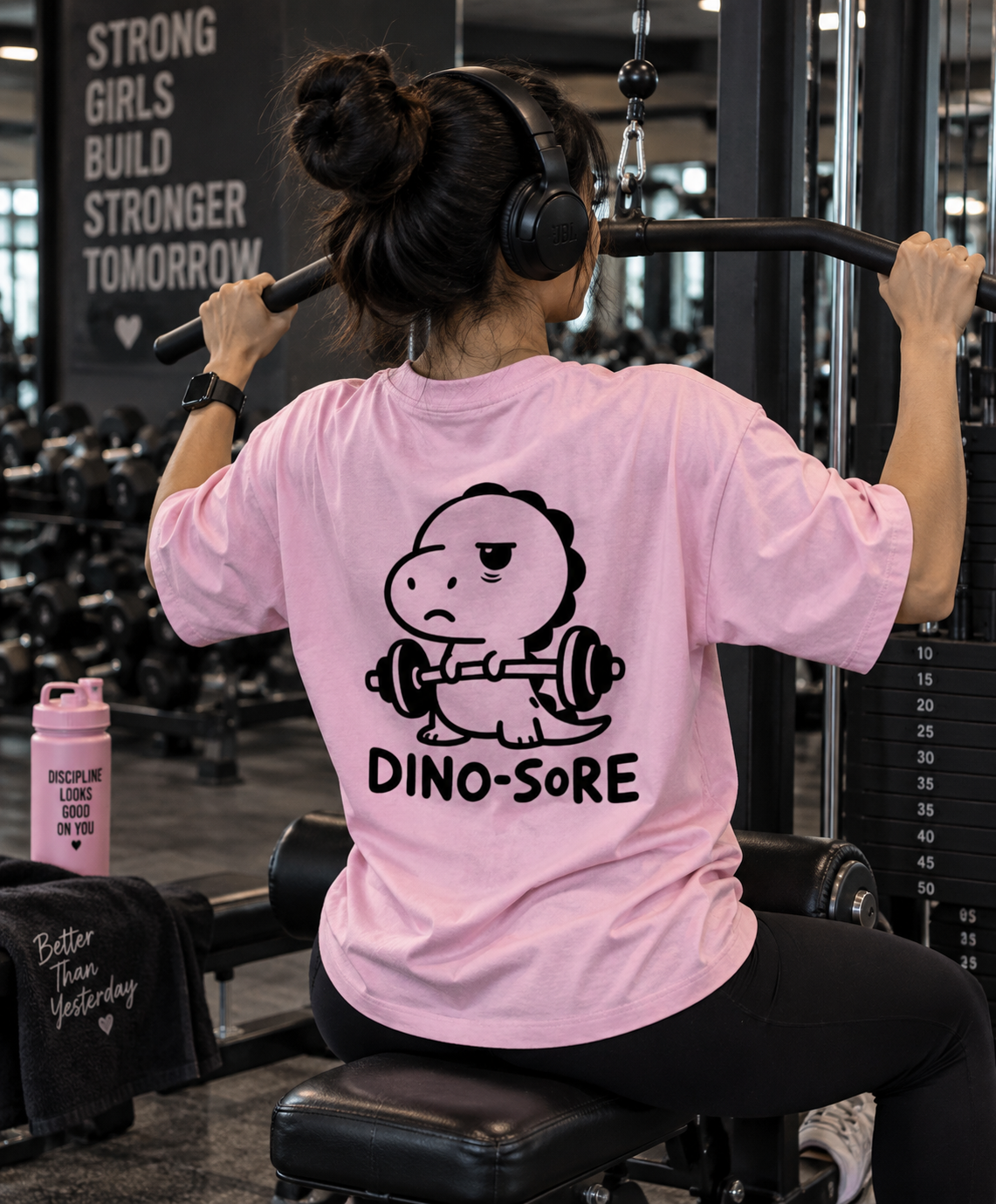 Female model wearing pink Dino-Sore oversized T-shirt back print in gym