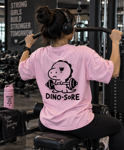 Female model wearing pink Dino-Sore oversized T-shirt back print in gym