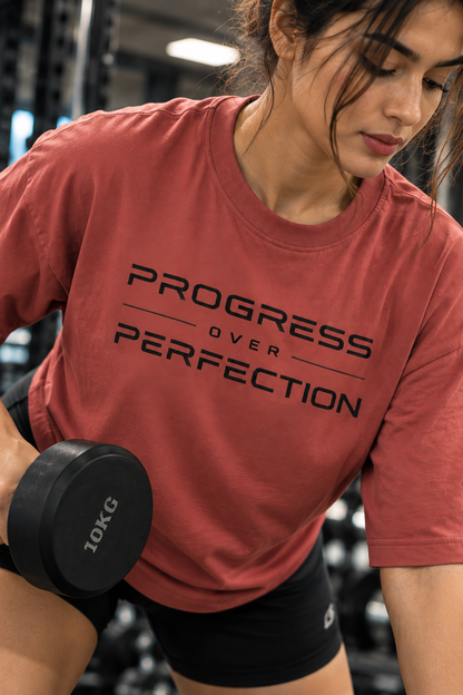Woman performing a bench-supported dumbbell row in a muted red Progress Over Perfection T-shirt