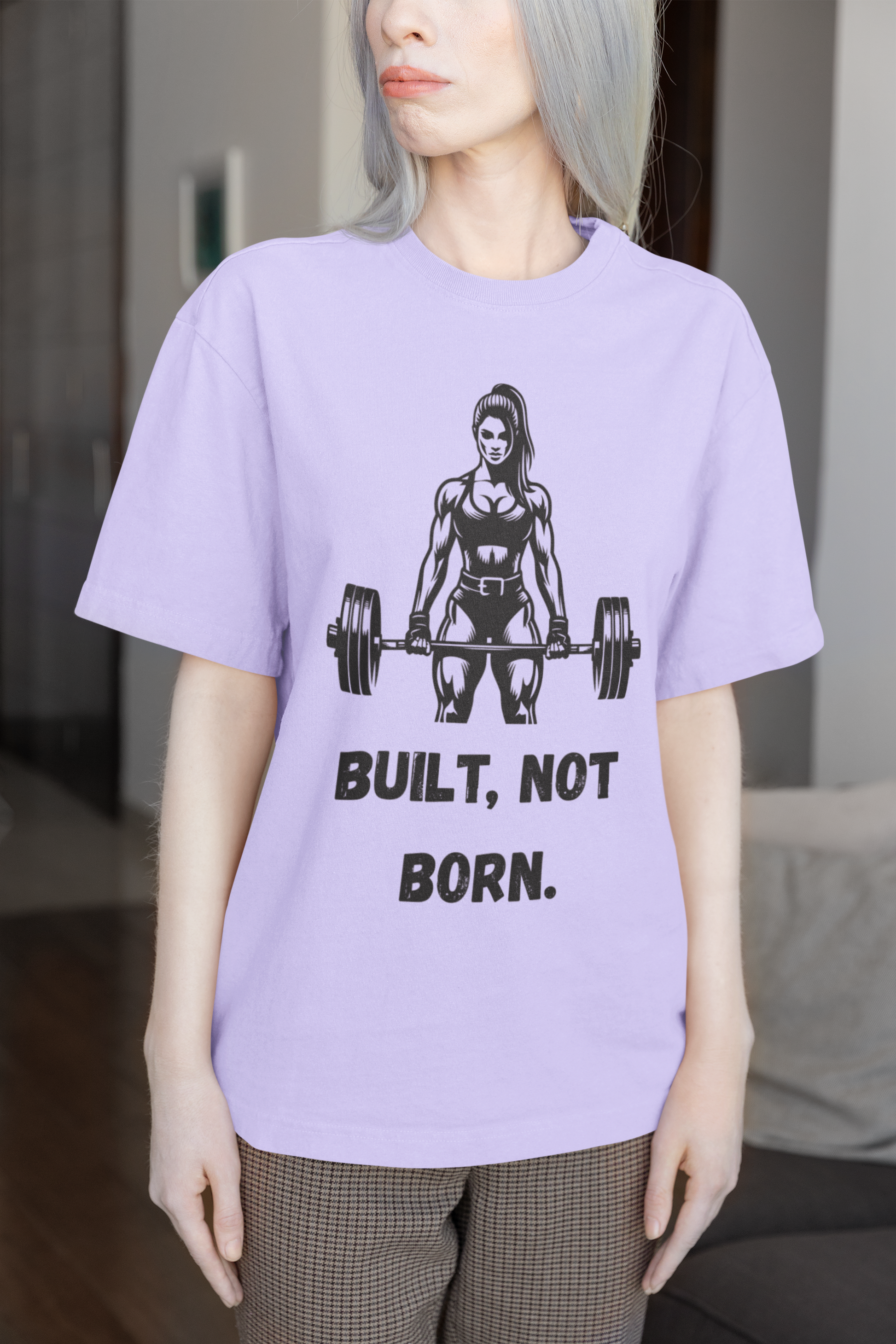 Person wearing a purple t-shirt with a graphic and text 'BUILT, NOT BORN.'