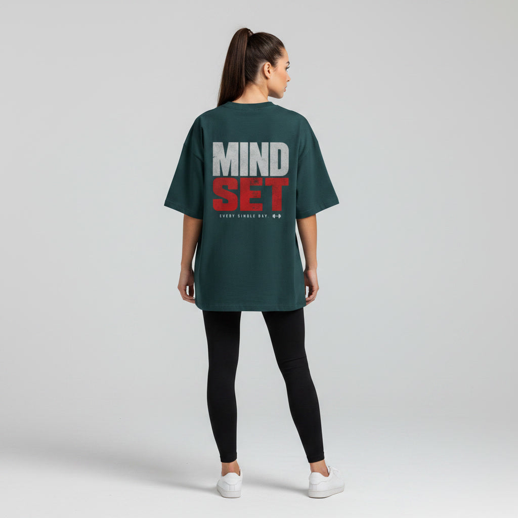 Back view of woman wearing dark green Mind Set oversized T-shirt with motivational back print